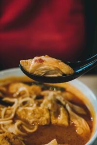 a spoon is holding a bowl of soup with noodles